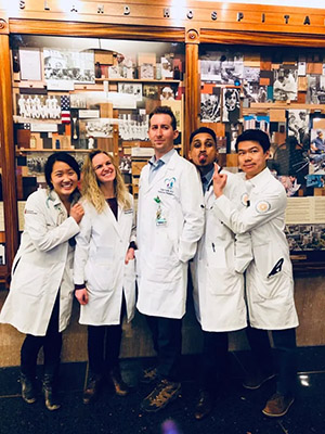 five people in white coats posing for a photo