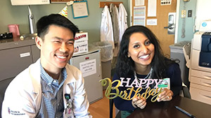 two people posing for a photo while one holds a sign that says happy birthday