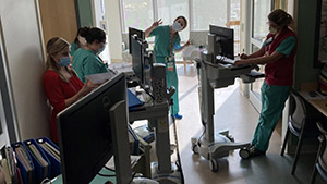 several people working on rolling workstations in a hospital hallway