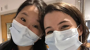 two people wearing PPE masks and posing for a photo