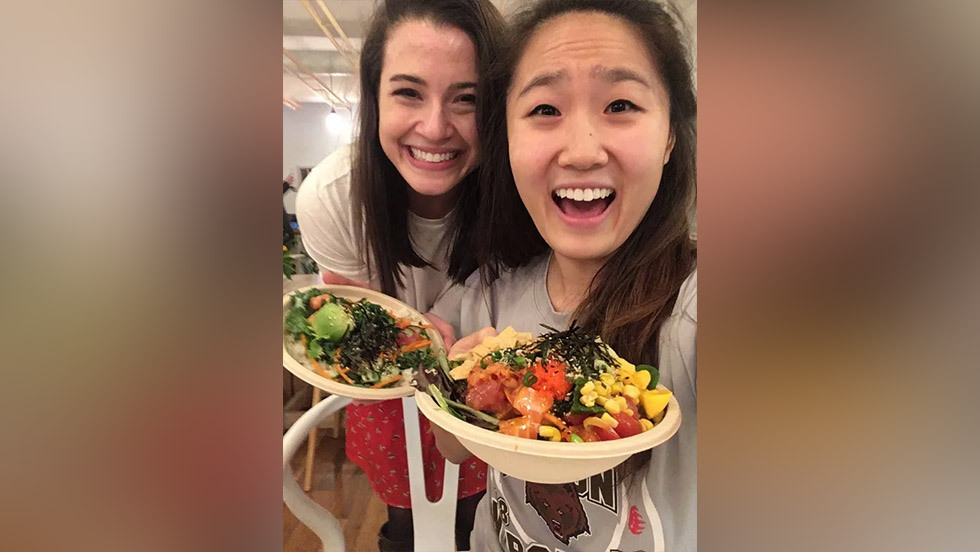 two people smiling and showing off bowls of food
