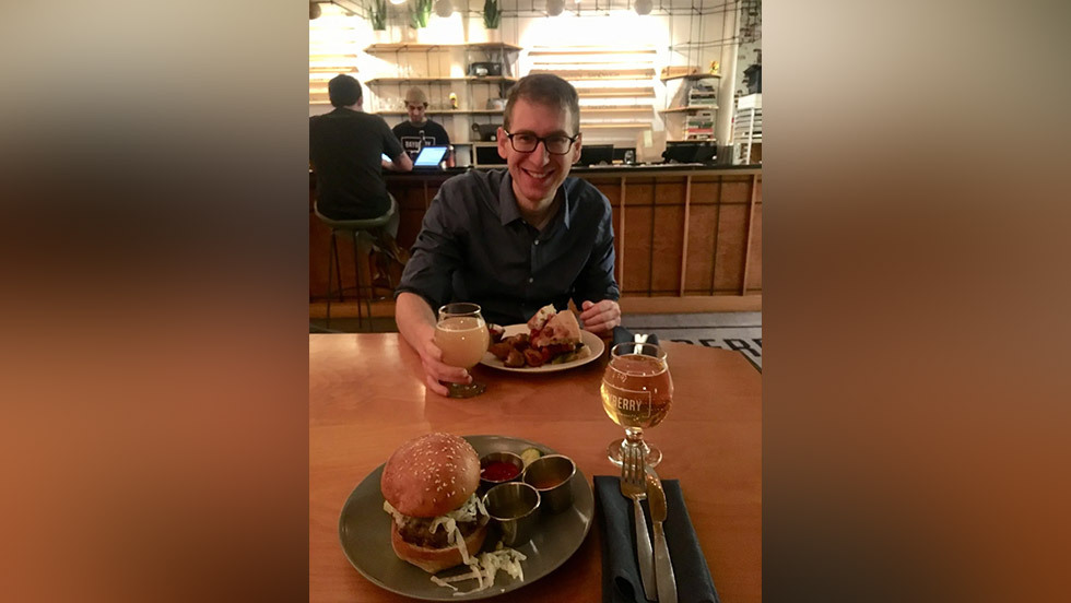 person smiling at a table of a dimly lit restaurant
